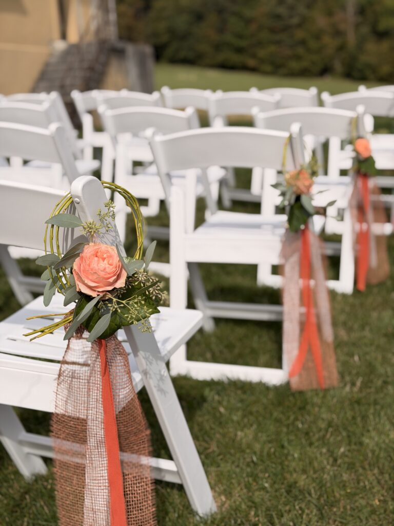 Chaises blanches décorées de roses pour une cérémonie laïque en plein air au Domaine Pré-Jeantet